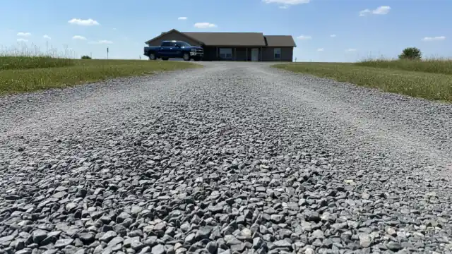 Crushed stone gravel driveway leading to a rural residential home